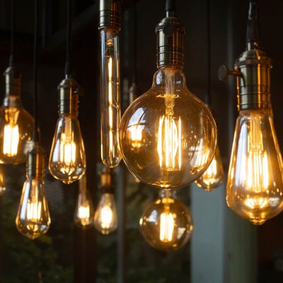 A bunch of light bulbs hanging from the ceiling. The bulbs are all different shapes and sizes, but they all have a warm, yellow glow. The scene gives off a cozy, inviting atmosphere